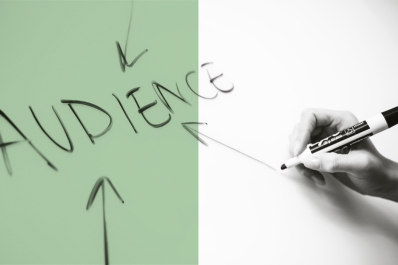 The word "audience" written on a whiteboard with a hand drawing arrows towards the word